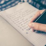 Itinerary Planning - person writing bucket list on book