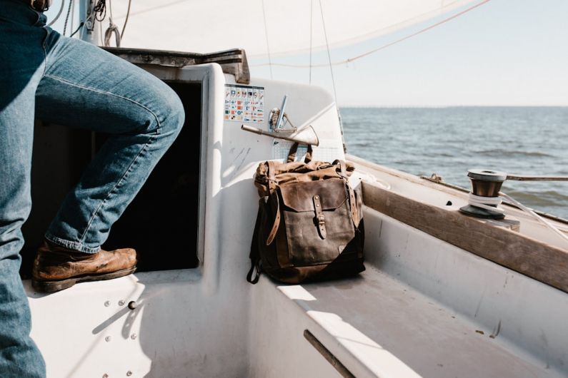 Nautical Chart - person in blue denim jeans on yacht beside brown bag