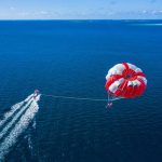 Maldives Ocean - a person is parasailing over the ocean with a boat